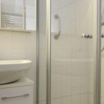 Badezimmer mit Dusche und Waschbecken. Weiße Fliesen und moderne Armaturen.