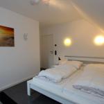 Schlafzimmer mit Doppelbett, Wandbild und Stehlampe.