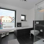 Badezimmer mit Dusche, Badewanne und Fensterblick.