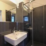 Badezimmer mit Dusche, Waschbecken und Spiegel