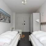 Zwei Betten, Wandbild, Schrank und Stehlampe im Schlafzimmer.