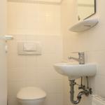 Badezimmer mit Toilette, Waschbecken und Spiegel an der Wand.