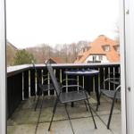 Terrasse mit Tisch und Stühlen, Blick auf Dächer und Bäume.