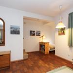 Zimmer mit Holzboden, Spiegel, Fenster und Bett im Hintergrund.