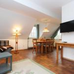 Wohn- und Essbereich mit Sofa, Esstisch, Fernseher und Holzboden.