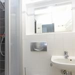 Badezimmer mit Dusche, Waschbecken und Spiegel.