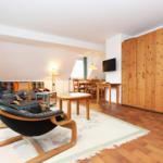 Wohnbereich mit Ledersessel, Sofa, Esstisch und Holzschrank.