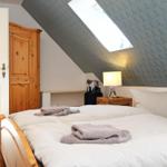 Schlafzimmer mit Dachschrägen, Bett, Nachttisch und Schrank.