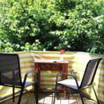 Terrasse mit zwei Stühlen und Tisch vor grüner Hecke.