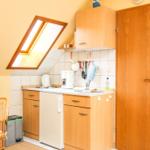 Küche mit Holzschränken, Spüle und Kühlschrank unter Dachschräge mit Dachfenster.