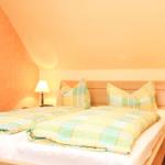 Ein Schlafzimmer mit Doppelbett, zwei Nachttischen und zwei Lampen. Die Wände sind orange und weiß gestrichen.