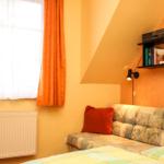 Schlafzimmer mit Bett, Sofa und Fenster mit Vorhängen.