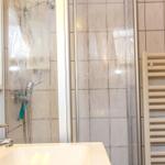 Badezimmer mit Dusche, Waschbecken und Heizkörper