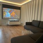 Ein Wohnzimmer mit einem Sofa, einem Glas-Tisch und einer Projektionswand.