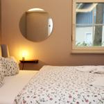 Ein Schlafzimmer mit Bett, Spiegel und Fenster. Auf dem Bett liegen Handtücher.