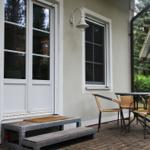 Terrasse mit Tisch und Stühlen vor einer Haustür mit Fenstern.