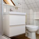 Badezimmer mit Waschbecken, Toilette und Dusche unter Dachschrägen.