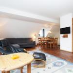 Wohn- und Essbereich mit Sofa, Esstisch und Fernseher an der Wand.