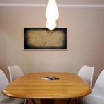 Esszimmer mit Holztisch, vier weißen Stühlen und Wandbild mit Vögeln.