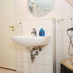 Bad mit Waschbecken, Spiegel und Handtuchhalter an der Wand.
