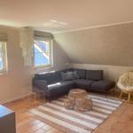 Wohnzimmer mit Sofa, Rattanmöbeln und Fenstern.