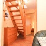 Treppenhaus mit Holztreppe, Schrank und Couch im Vordergrund.