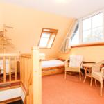 Dachgeschosszimmer mit Schlafcouch, zwei Stühlen und großem Fenster.