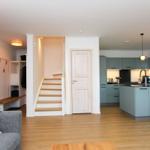 Wohnung mit Küche, Treppenhaus und Schlafzimmer. Holzboden und blaue Küchenmöbel.