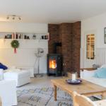 Wohnzimmer mit Kamin, weißen Sofas und Holztisch.