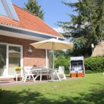 Haus mit Terrasse, Gartenmöbeln und Strandkorb unter einem Sonnenschirm.