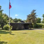 Holzhütte mit Flagge auf grünem Rasen umgeben von Bäumen