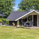 Moderne Hütte mit Terrasse, Garten und Sitzgelegenheiten unter einem Sonnenschutz.