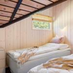 Zwei Betten in einem Holzhauszimmer mit Fenster und Schrank.