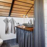 Badezimmer mit Holzdecke, Waschtisch und Toilette