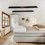 Schlafzimmer mit Bett, Kleiderkabinett und Fenster. Holzgestell und weiße Möbel.