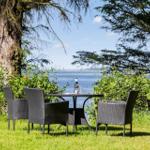 Garten-Tisch mit vier Stühlen vor Wasser und Bäumen