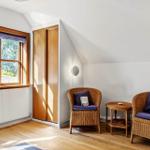 Zimmer mit zwei Rattan-Stühlen, kleinem Tisch und Fenster mit Blick auf Bäume.