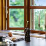 Küchenfenster mit Kerzen, Gewürzstreuer und Zutaten auf Arbeitsfläche.