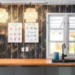 Küche mit Holzschrank, Fenster, Wandtapete und zwei Leuchten.