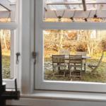 Durch das Fenster ist ein Garten mit Tisch und Stühlen zu sehen.