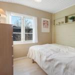 Schlafzimmer mit Bett, Fenster, Schrank und Wandregal.