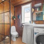Badezimmer mit Dusche, Toilette, Waschbecken und Waschmaschine.