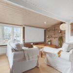 Wohnzimmer mit zwei Sofas, Fernseher und großen Fenstern.