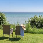 Zwei Stühle auf einer Wiese mit Blick auf das Meer.