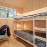Zimmer mit Doppelstockbett, Schreibtisch und Stuhl. Holzwände und -boden.