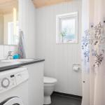 Badezimmer mit Waschmaschine, Toilette und Duschvorhang mit Muster.