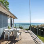 Terrasse mit Tisch und Stühlen bietet Meerblick. Holzdeck und Metallgeländer.