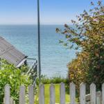Vom Garten aus Blick auf das Meer mit weißem Zaun und grüner Vegetation.