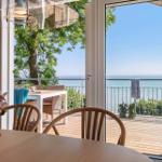 Terrasse mit Meerblick, Tisch und Stühle, Blick durch Glastüren ins Innere.