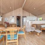 Ein Raum mit Essbereich und Wohnbereich, Holzwand und -decke, Holzfußboden, Esstisch mit Stühlen und Sofa.